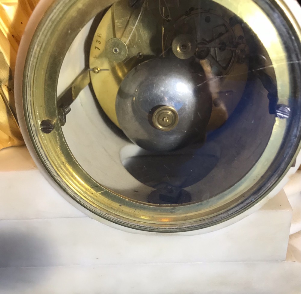 A Victorian gilt bronze and white marble mantel clock featuring a reclining classical female figure reading a book atop a stepped base. View VI