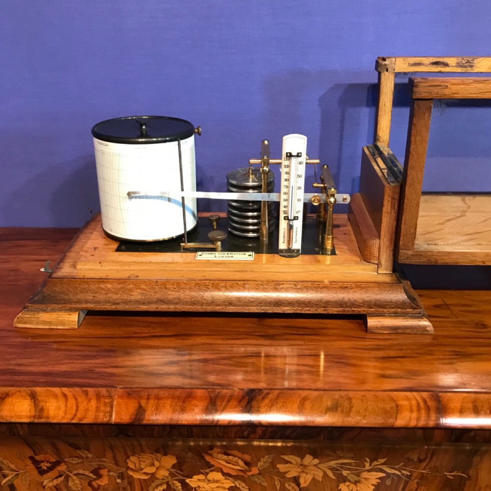 An antique barograph with a brass mechanism and paper recording drum encased in a glazed oak frame topped with a brass handle. View V