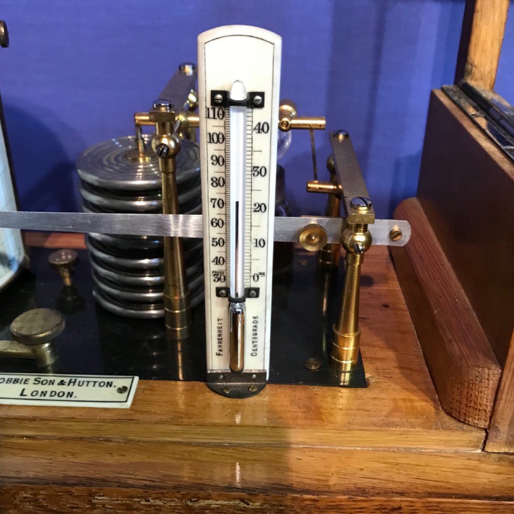 An antique barograph with a brass mechanism and paper recording drum encased in a glazed oak frame topped with a brass handle. View VI