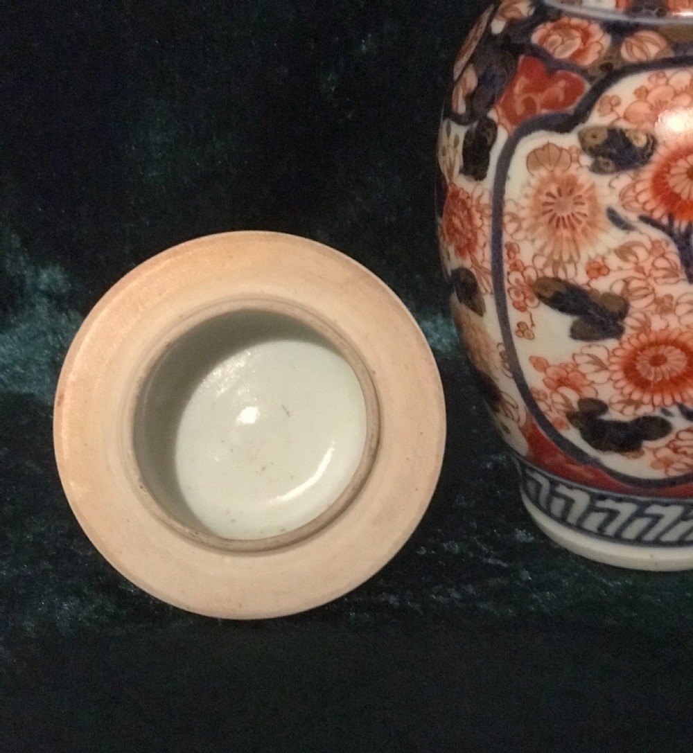 An antique Japanese Imari porcelain lidded vase decorated with intricate orange-red chrysanthemums and cobalt blue floral panels against a white glazed ground. View III