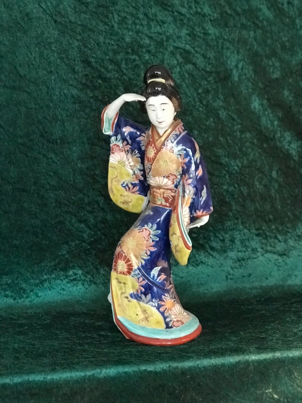 A Japanese Meiji period glazed porcelain figure depicting a standing woman in a hand-painted floral kimono shielding her eyes. View VI
