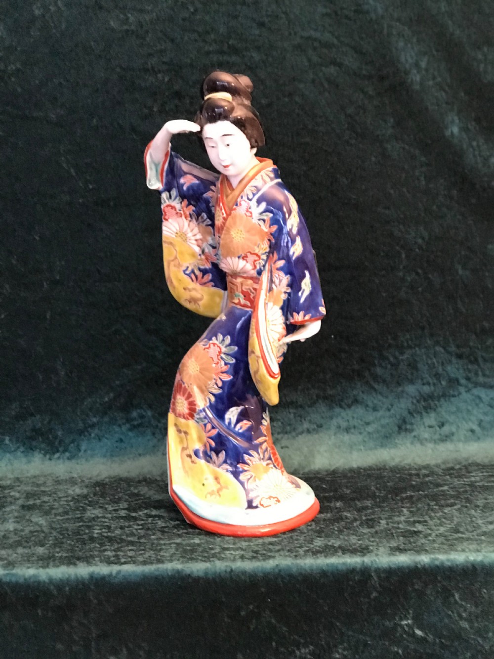 A Japanese Meiji period glazed porcelain figure depicting a standing woman in a hand-painted floral kimono shielding her eyes. View VII