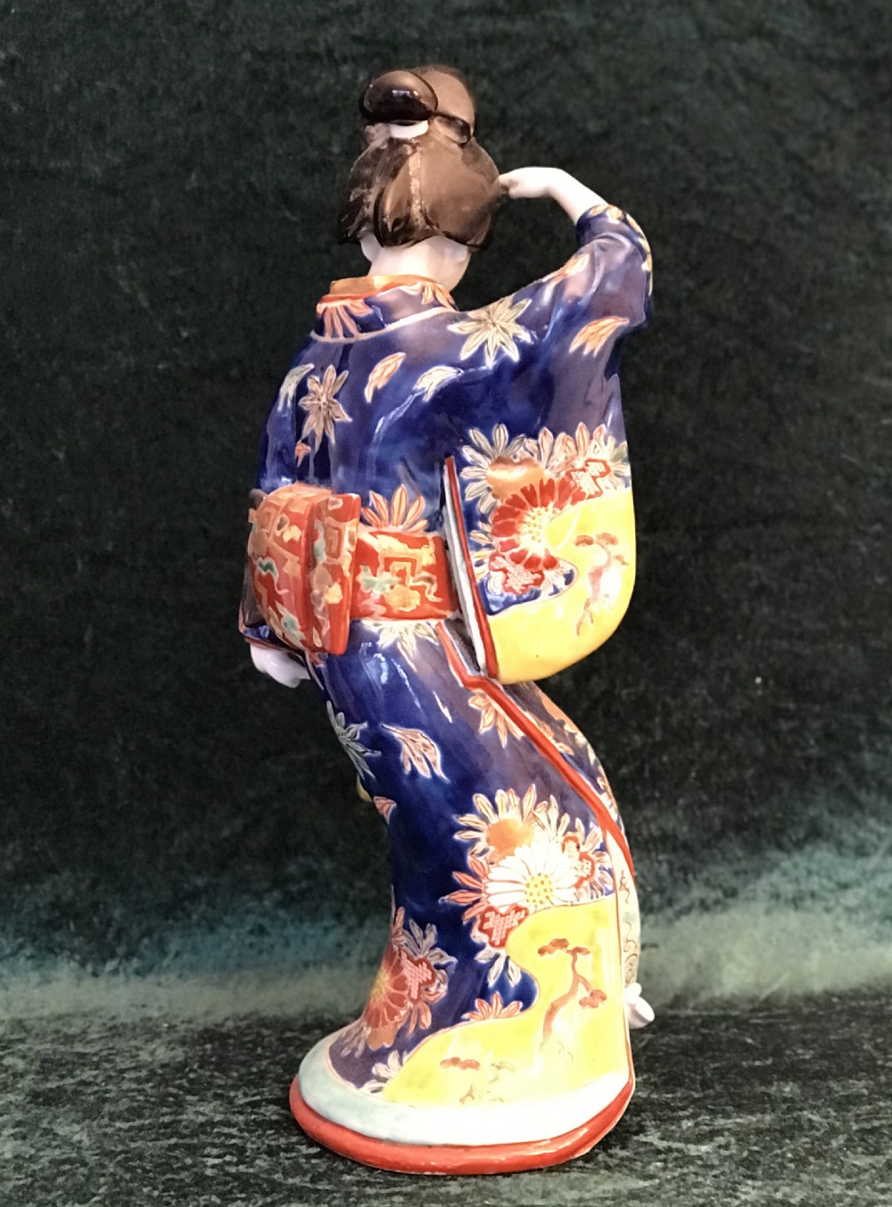 A Japanese Meiji period glazed porcelain figure depicting a standing woman in a hand-painted floral kimono shielding her eyes. View VIII