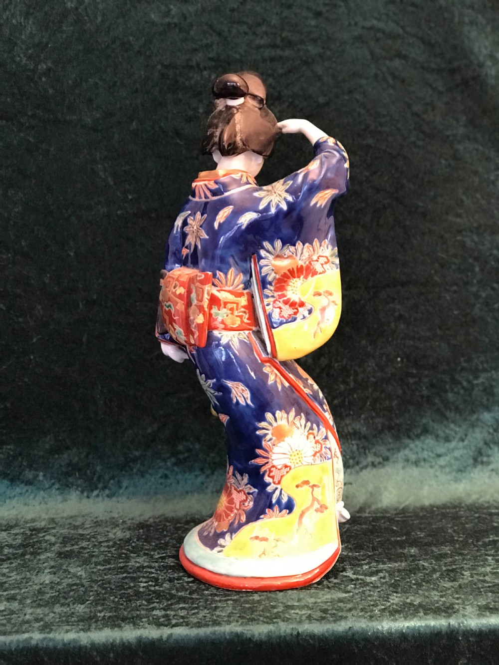 A Japanese Meiji period glazed porcelain figure depicting a standing woman in a hand-painted floral kimono shielding her eyes. View IX