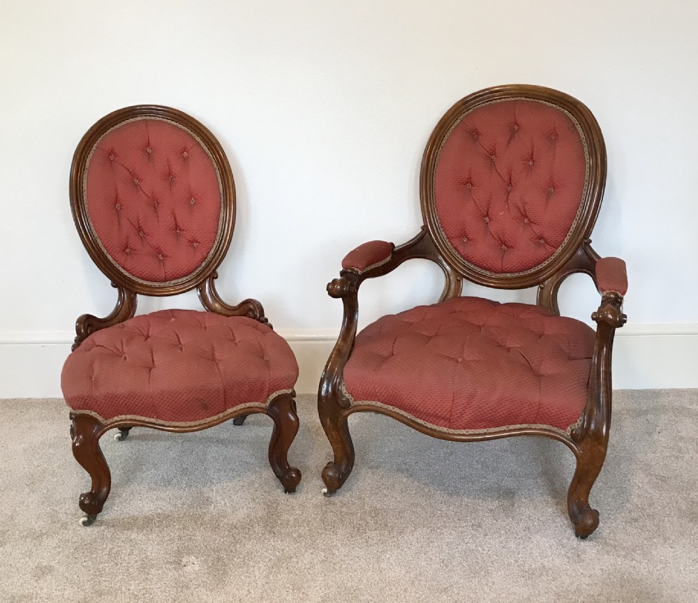 A pair of mid-Victorian walnut chairs upholstered in deep-buttoned red fabric with oval backrests and cabriole legs.