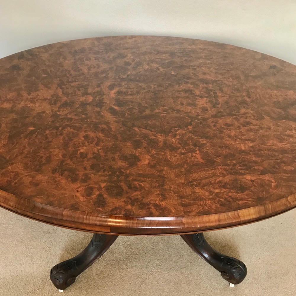 A Victorian tilt-top pedestal table with its circular top locked vertically on a carved wooden base with castors. View VIII