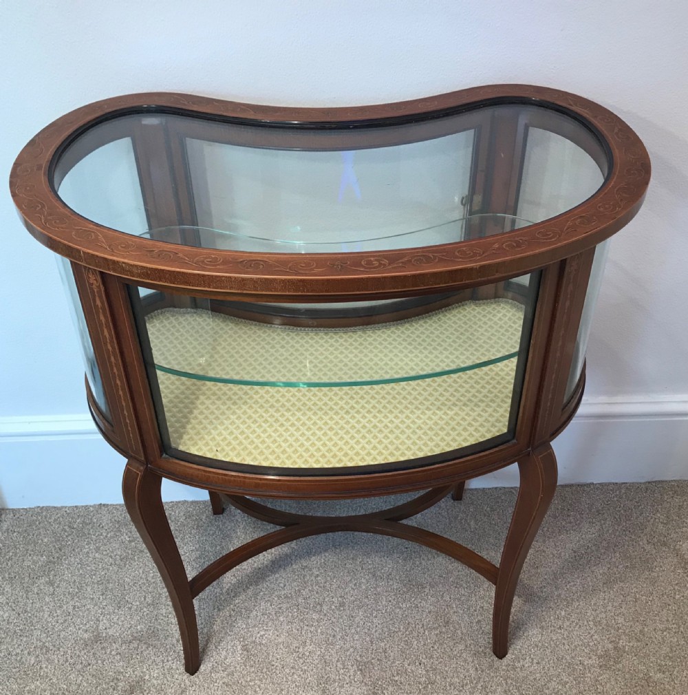 An Edwardian kidney-shaped mahogany bijouterie table with glazed top and sides, floral inlay, slender curved legs, and an interior glass shelf. View VII