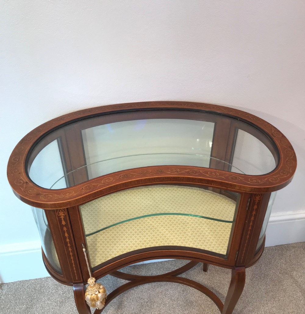 An Edwardian kidney-shaped mahogany bijouterie table with glazed top and sides, floral inlay, slender curved legs, and an interior glass shelf. View VIII