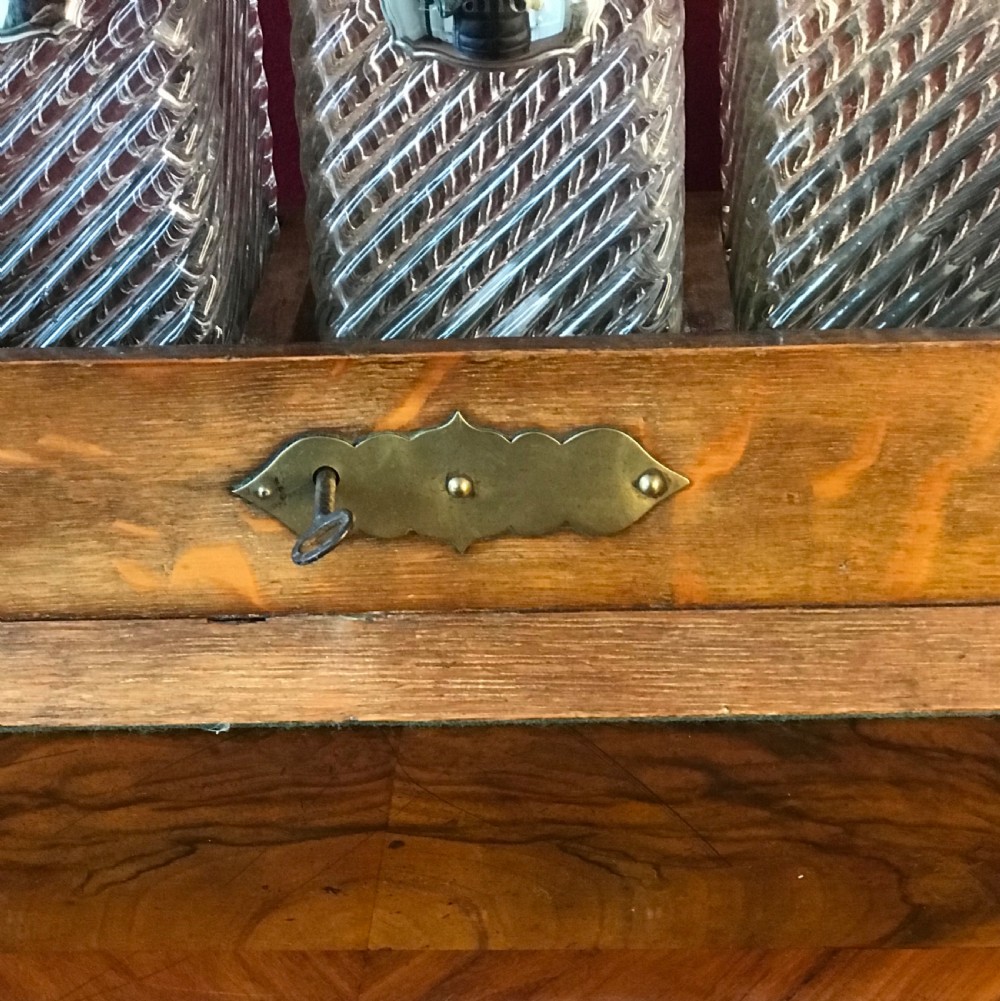 A 1930s oak tantalus with brass mounts and top carrying handle containing three cut glass decanters with round stoppers. View III