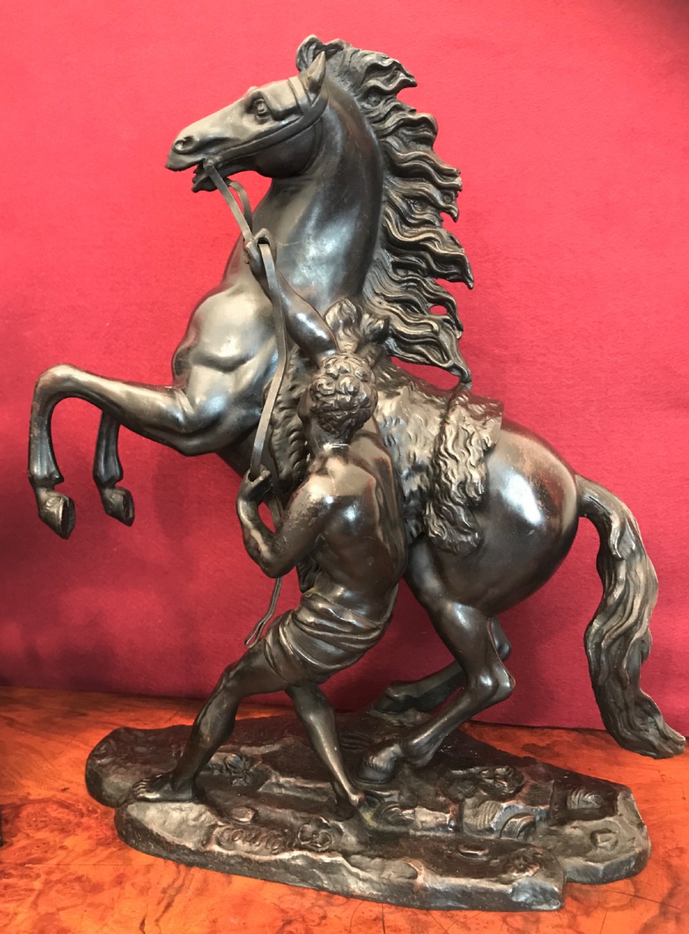 A pair of patinated dark bronze sculptures depicting rearing horses held by grooms on naturalistic bases. View III