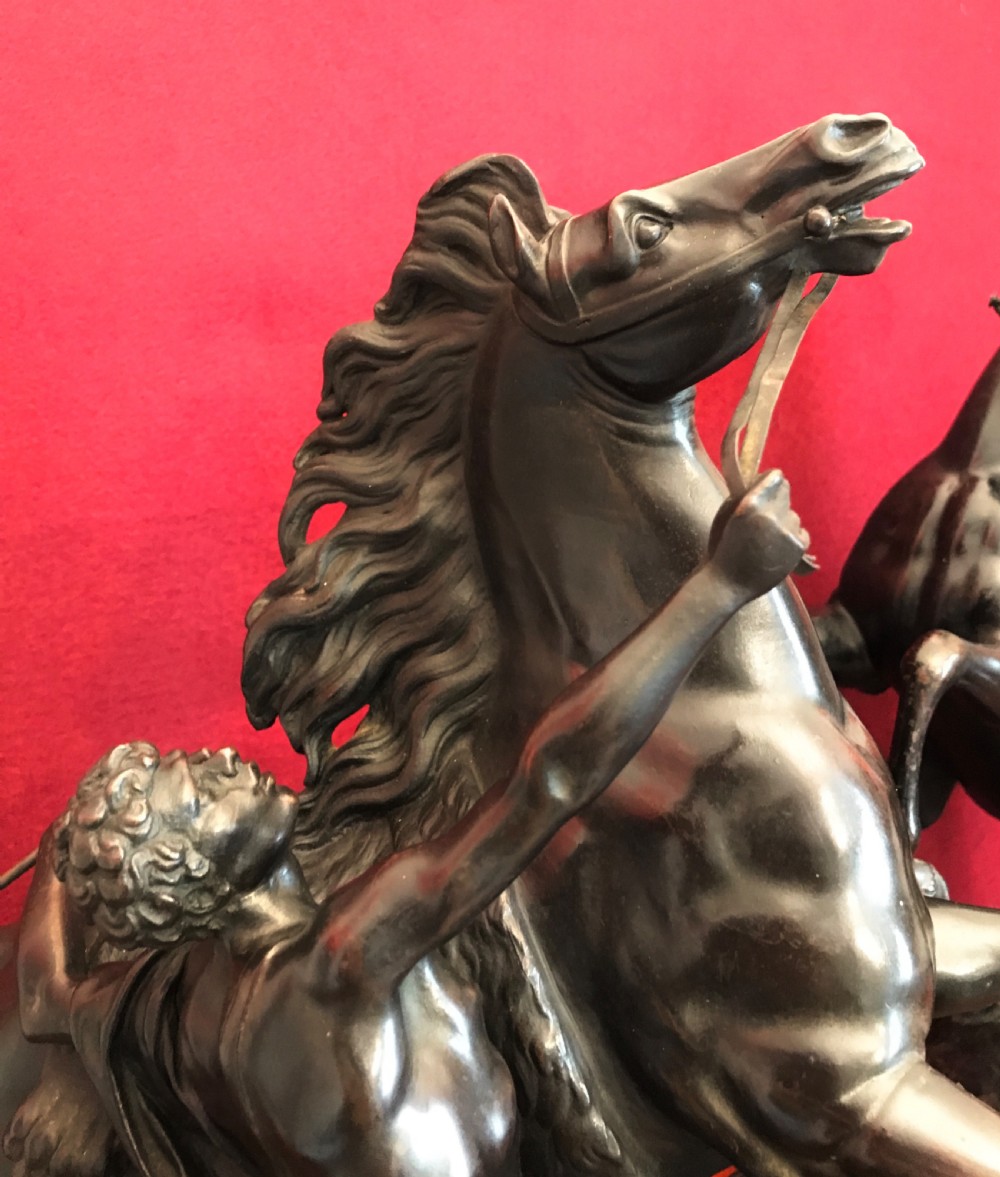 A pair of patinated dark bronze sculptures depicting rearing horses held by grooms on naturalistic bases. View VII
