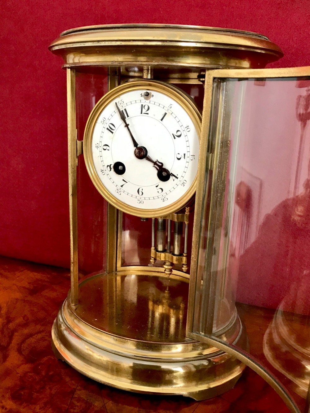 An oval late nineteenth-century French brass four-glass mantel clock featuring bevelled glass panels and an enamel dial with Roman numerals. View III