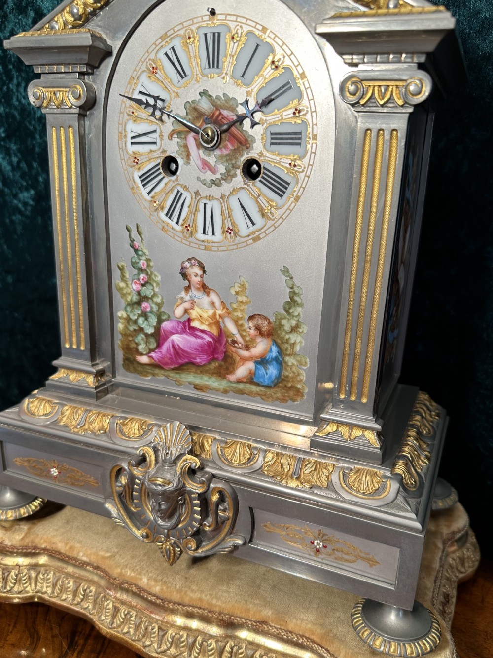 A 19th-century French mantel clock featuring a grey painted metal case decorated with gilded mounts and hand-painted porcelain panels topped with an urn finial. View XII