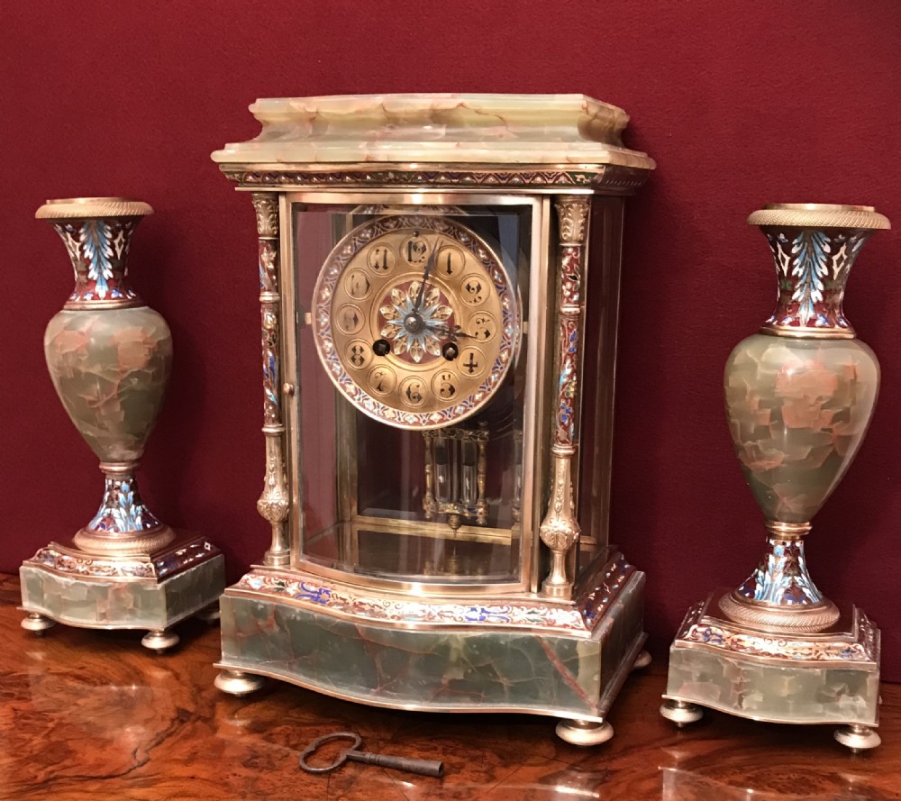 A late 19th-century French green onyx and champleve enamel mantel clock flanked by two matching garniture side vases.