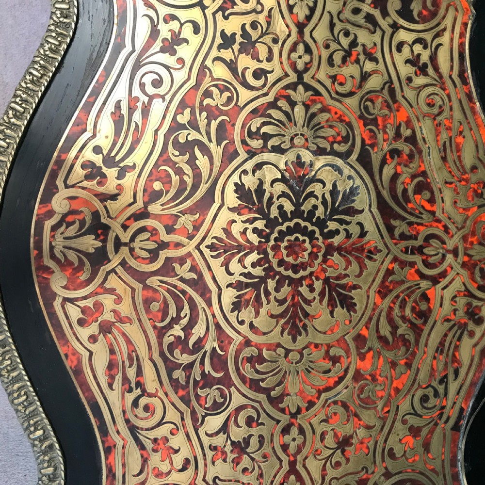 A French Napoleon III serpentine centre table decorated with red tortoiseshell and brass Boulle marquetry inlay, gilt-bronze mounts, and cabriole legs. View II