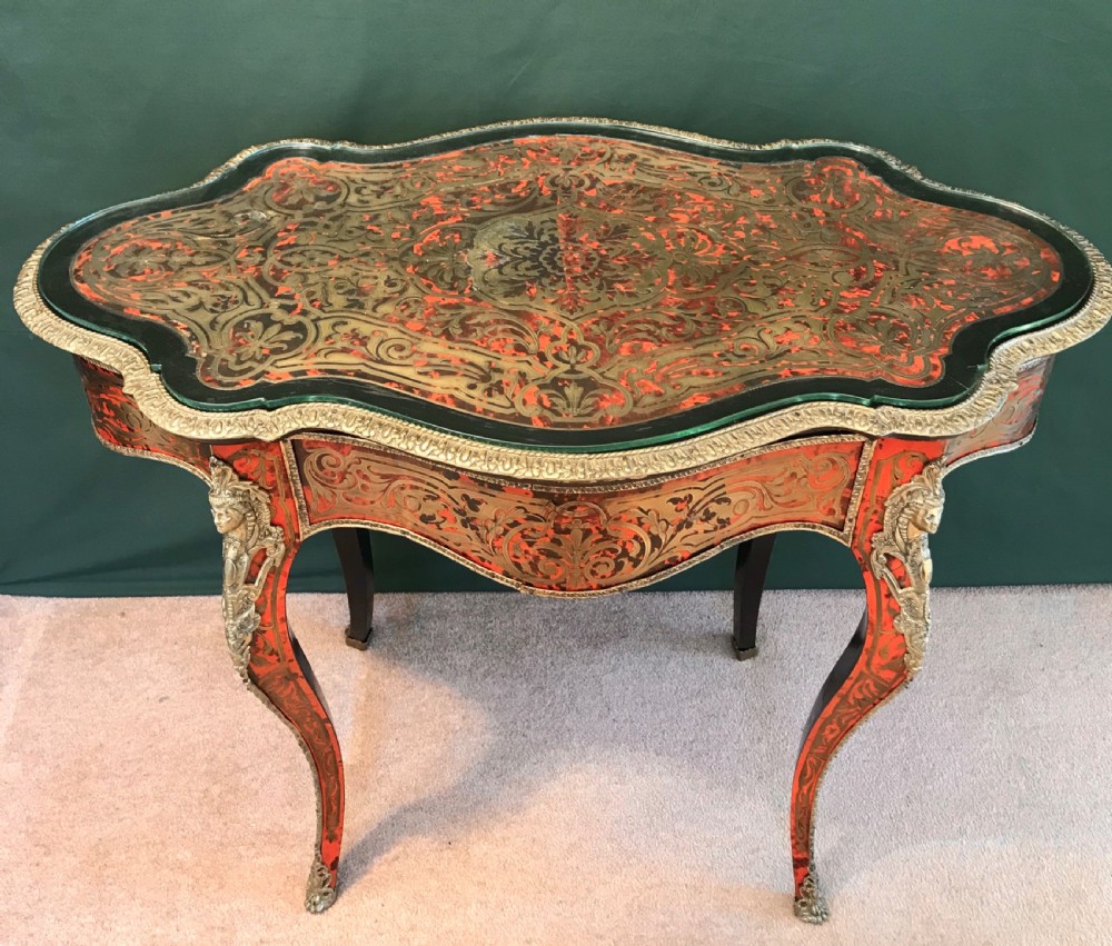 A French Napoleon III serpentine centre table decorated with red tortoiseshell and brass Boulle marquetry inlay, gilt-bronze mounts, and cabriole legs. View V