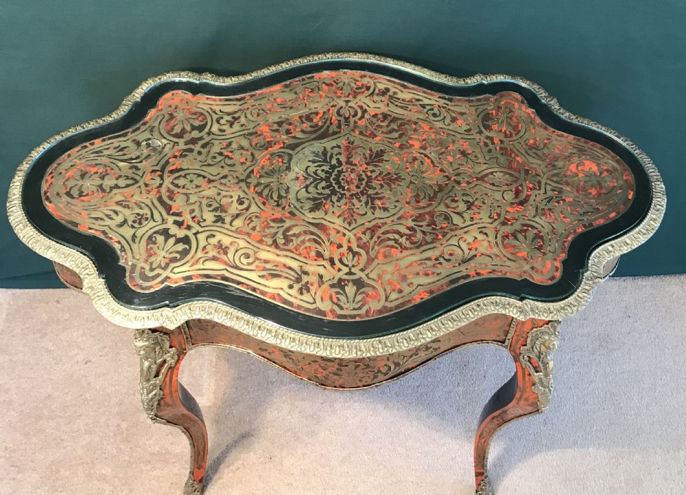 A French Napoleon III serpentine centre table decorated with red tortoiseshell and brass Boulle marquetry inlay, gilt-bronze mounts, and cabriole legs. View X