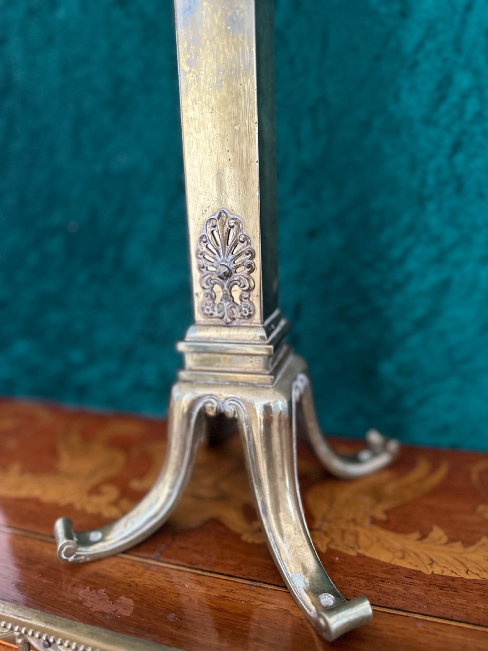 An antique brass twin-branch table lamp featuring neoclassical relief carvings on the central column and two curved arms with beige fabric shades. View II