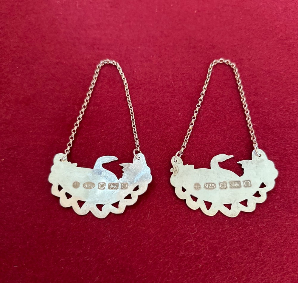A pair of clear Edwardian cut glass decanters featuring diamond facets, faceted stoppers, and silver decanter labels on chains. View III