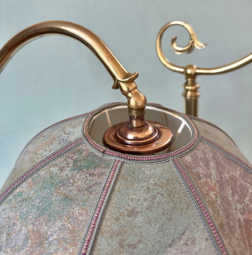 A pair of circa 1920 brass standard lamps featuring scrolled swan-neck arms, ornate cast bases, and scalloped domed lampshades. View V