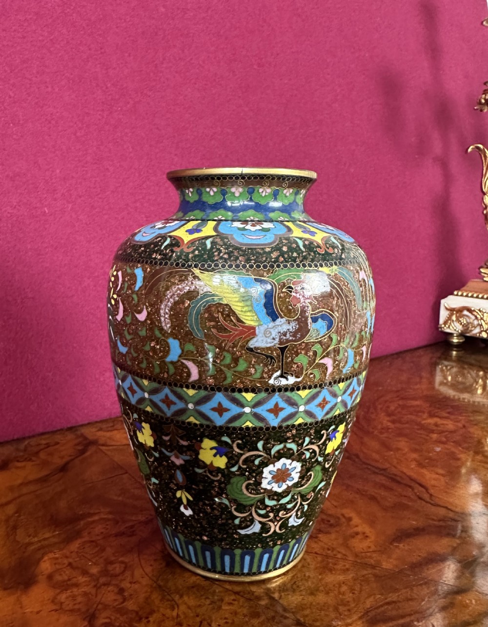A Japanese Meiji period cloisonne enamel vase decorated with bird and floral motifs against a goldstone speckled ground.
