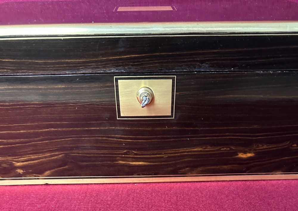 A dark rosewood campaign correspondence box featuring brass edge trim, a central rectangular brass nameplate, and a key inserted into the brass keyhole escutcheon. View II