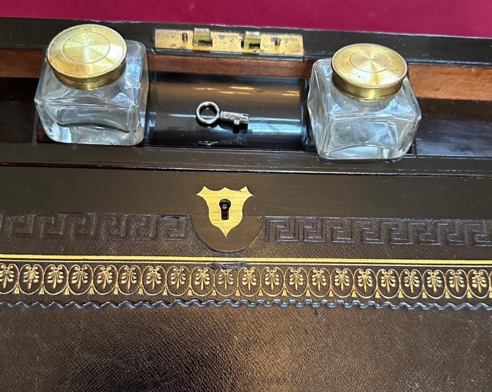 A dark rosewood campaign correspondence box featuring brass edge trim, a central rectangular brass nameplate, and a key inserted into the brass keyhole escutcheon. View VIII