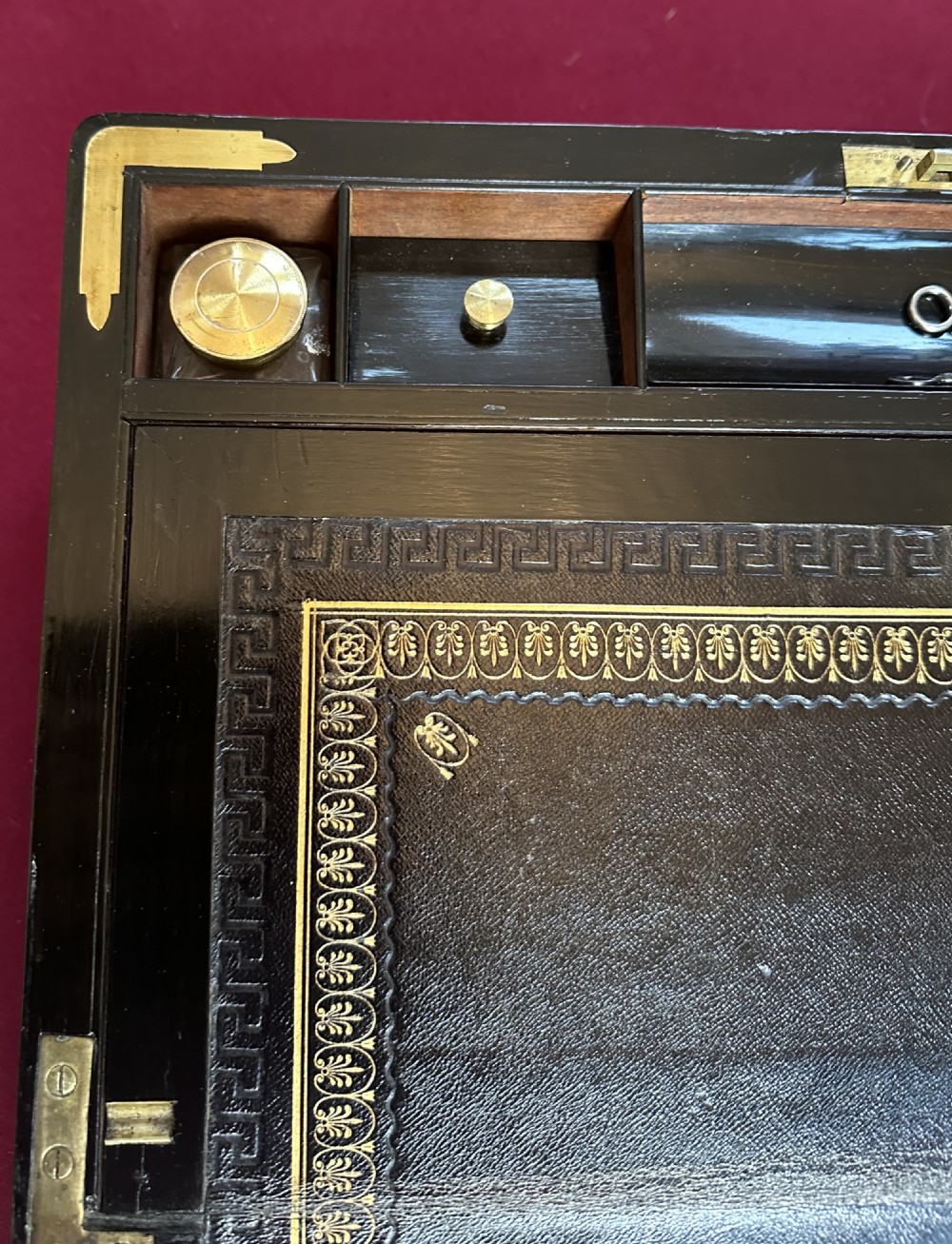 A dark rosewood campaign correspondence box featuring brass edge trim, a central rectangular brass nameplate, and a key inserted into the brass keyhole escutcheon. View X