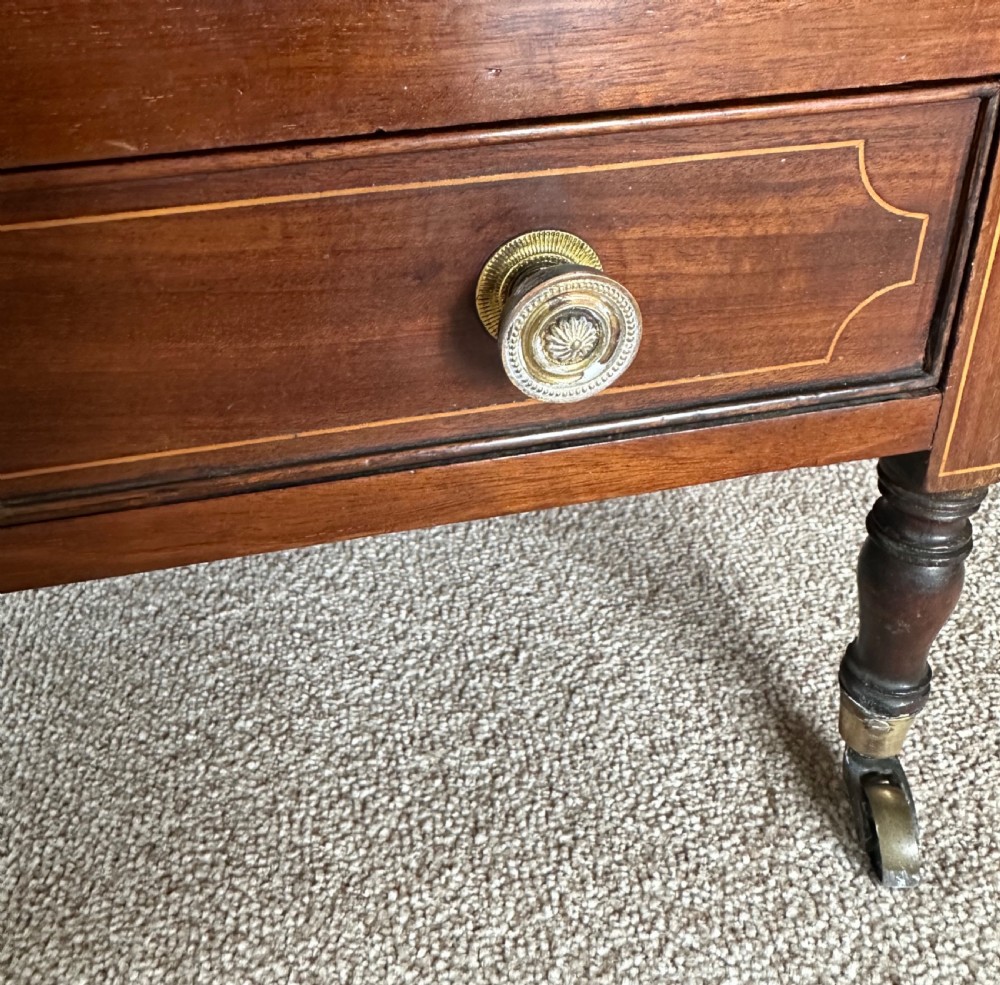An antique mahogany music canterbury featuring slatted divisions, boxwood inlay, a single lower drawer with brass knobs, and turned legs on castors. View VIII