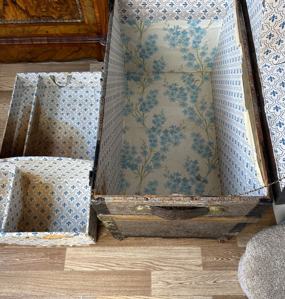 A Victorian dome top travelling trunk featuring embossed patterned metal casing, dark timber reinforcing slats, and brass corner mounts and central lock. View V