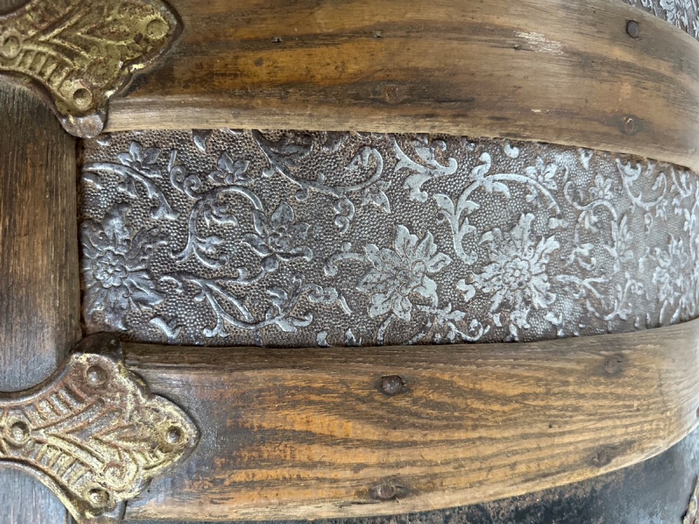 A Victorian dome top travelling trunk featuring embossed patterned metal casing, dark timber reinforcing slats, and brass corner mounts and central lock. View VIII