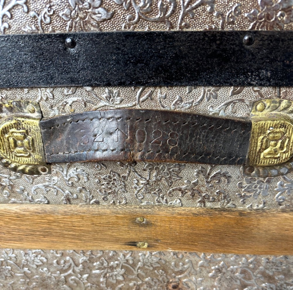 A Victorian dome top travelling trunk featuring embossed patterned metal casing, dark timber reinforcing slats, and brass corner mounts and central lock. View IX