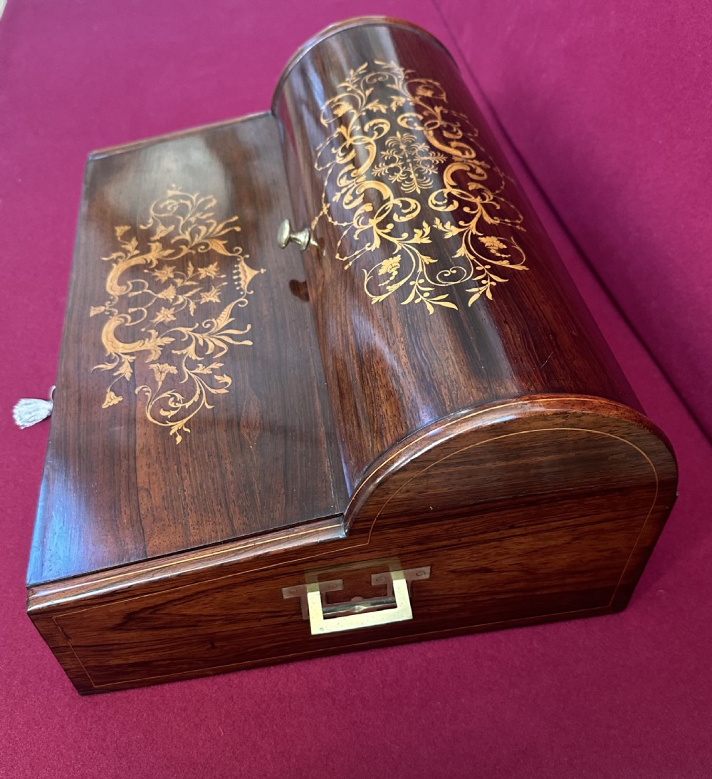 A Victorian dark rosewood writing slope box featuring delicate floral marquetry inlay, side brass handles, and a key with a tassel. View IV