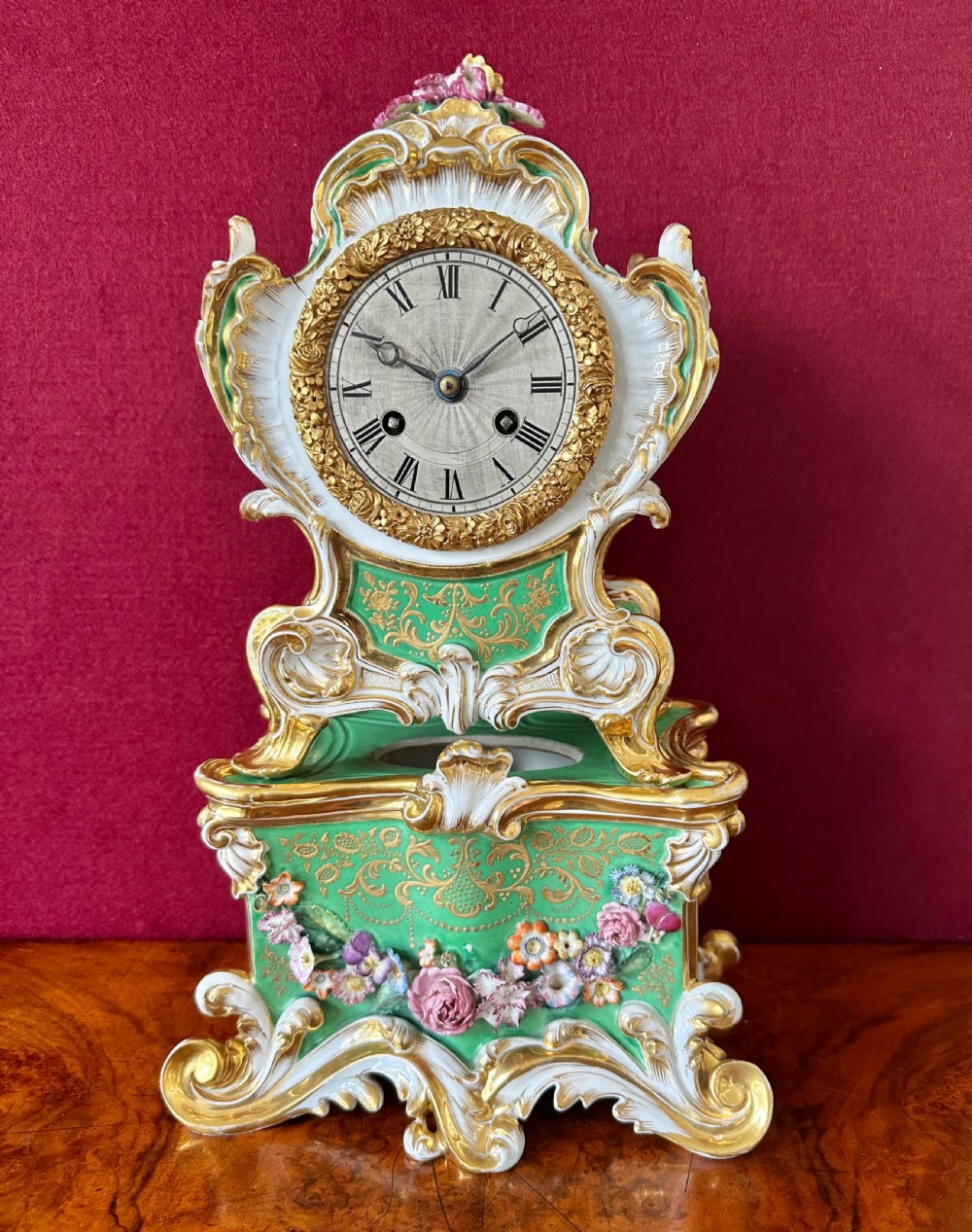 An early 19th-century French Rococo Revival porcelain mantel clock featuring green glaze, gilt scrollwork, and hand-moulded floral details. View II