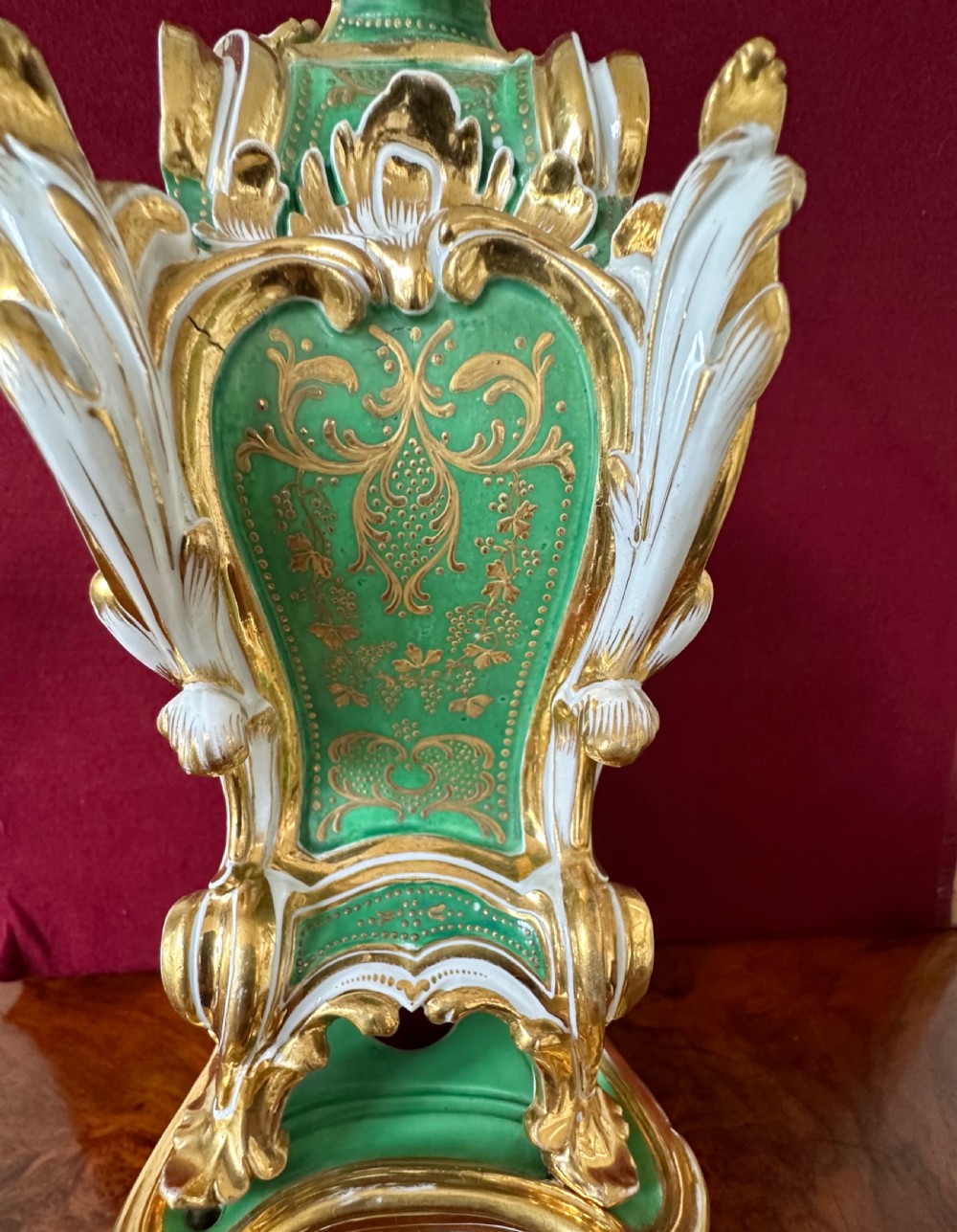 An early 19th-century French Rococo Revival porcelain mantel clock featuring green glaze, gilt scrollwork, and hand-moulded floral details. View V