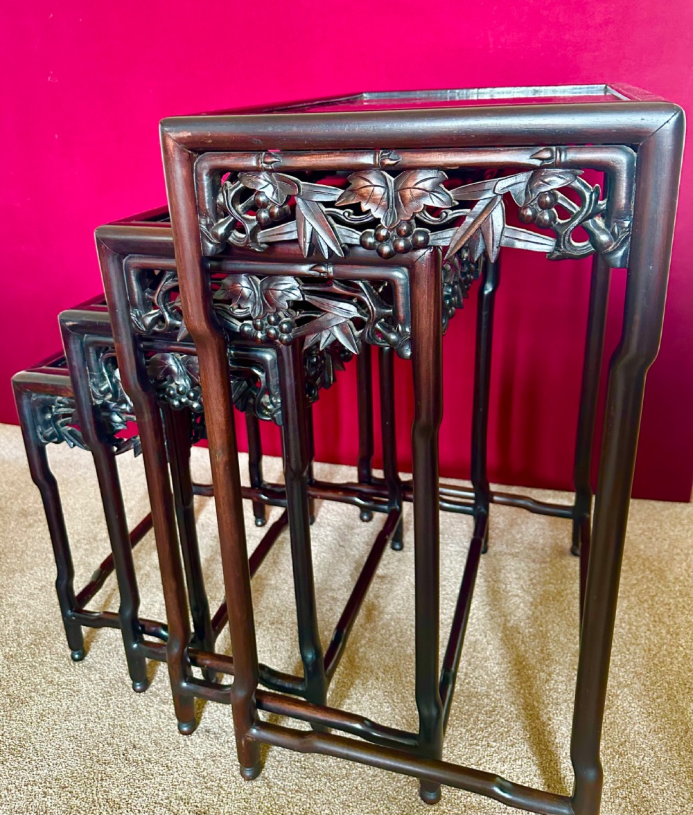 A set of four dark hardwood Chinese nesting tables featuring openwork carved bamboo aprons and faux-bamboo legs. View VI