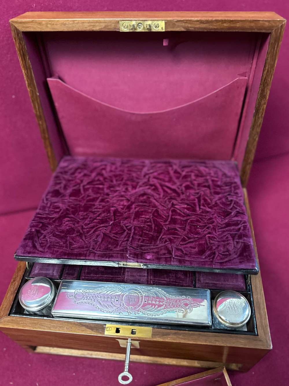 An open Victorian walnut travelling dressing case featuring an interior lid mirror, purple velvet compartments, glass jars with silver caps, and an opened lower drawer. View VII