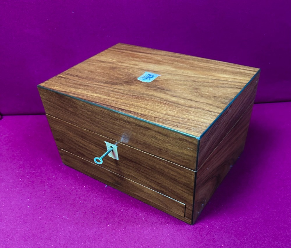 An open Victorian walnut travelling dressing case featuring an interior lid mirror, purple velvet compartments, glass jars with silver caps, and an opened lower drawer. View IX
