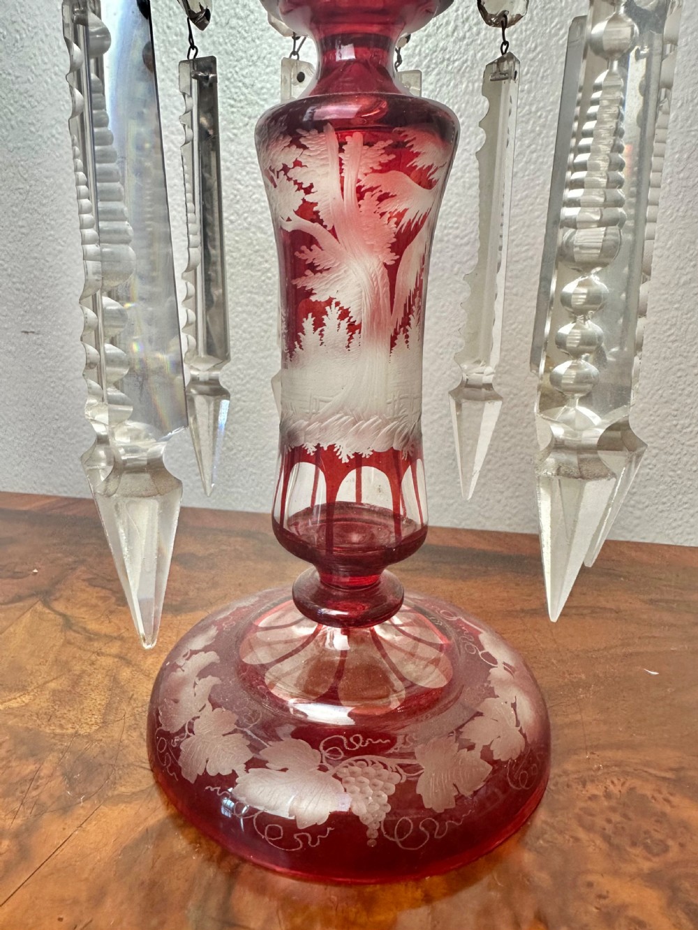 A pair of 19th-century Victorian ruby red flash glass lustres with acid-etched stag scenes, scalloped rims, and suspended clear crystal prism drops. View II