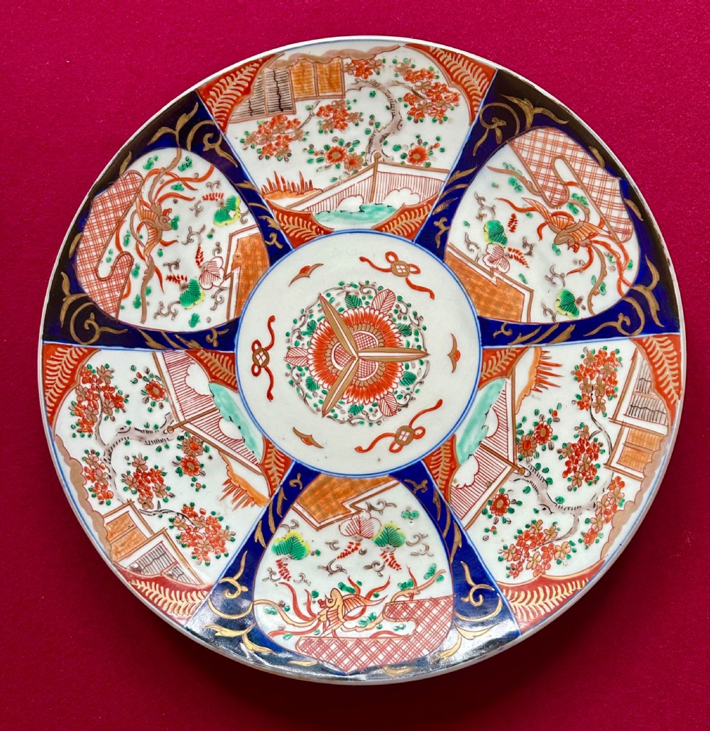 A circular Japanese Imari porcelain charger featuring cobalt blue and iron-red panelled decorations with floral motifs and phoenix figures.