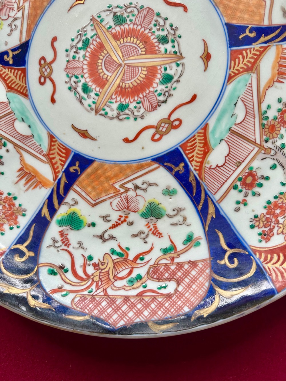 A circular Japanese Imari porcelain charger featuring cobalt blue and iron-red panelled decorations with floral motifs and phoenix figures. View II