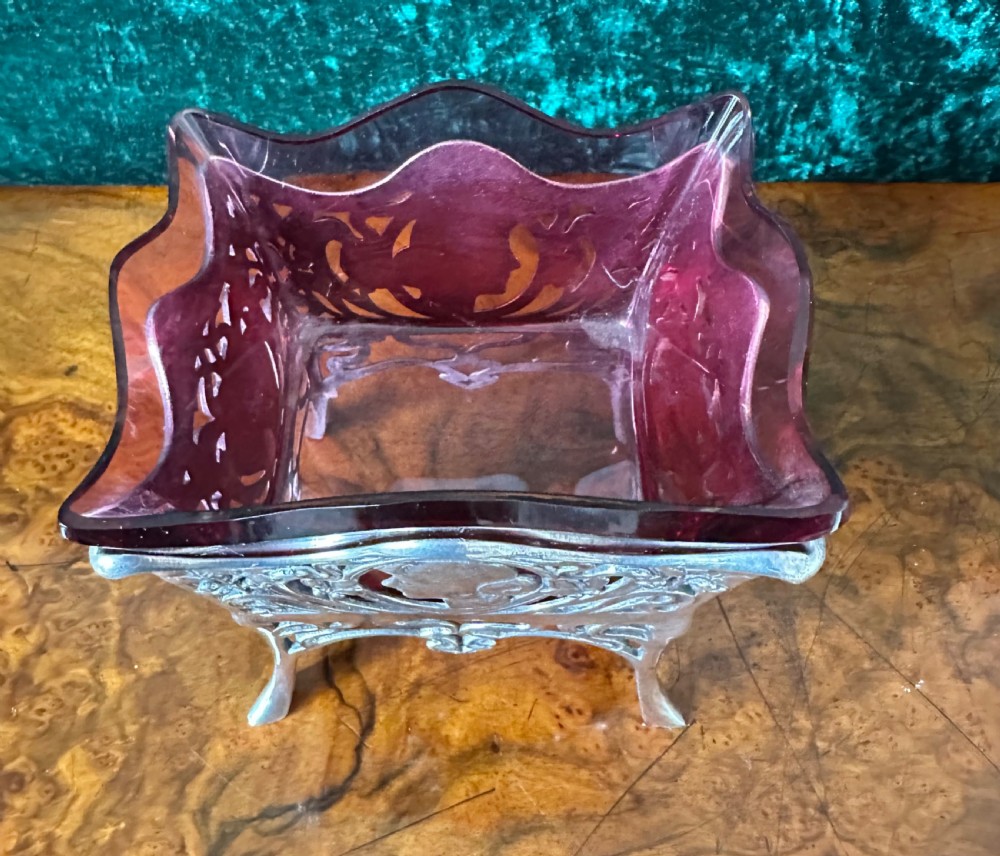 An Art Nouveau silver-plated pierced metal frame featuring a maiden profile with a ruby red glass liner. View II