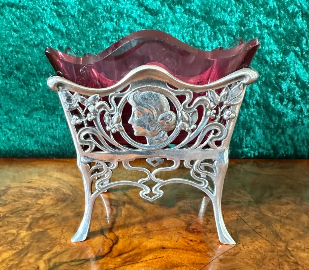 An Art Nouveau silver-plated pierced metal frame featuring a maiden profile with a ruby red glass liner. View III