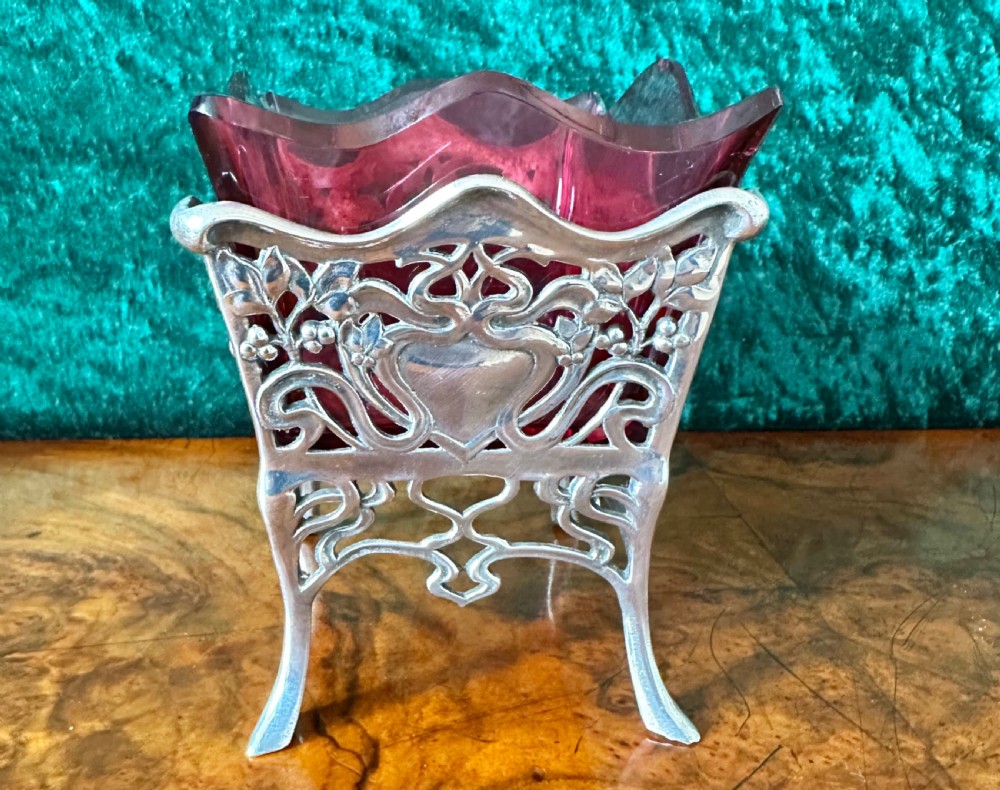 An Art Nouveau silver-plated pierced metal frame featuring a maiden profile with a ruby red glass liner. View V