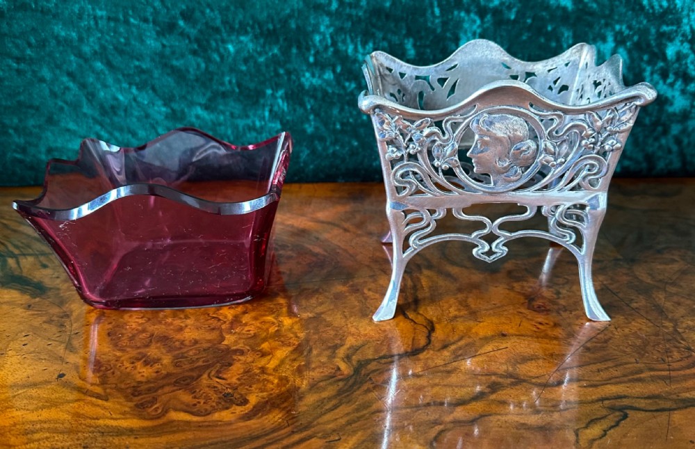 An Art Nouveau silver-plated pierced metal frame featuring a maiden profile with a ruby red glass liner. View VI