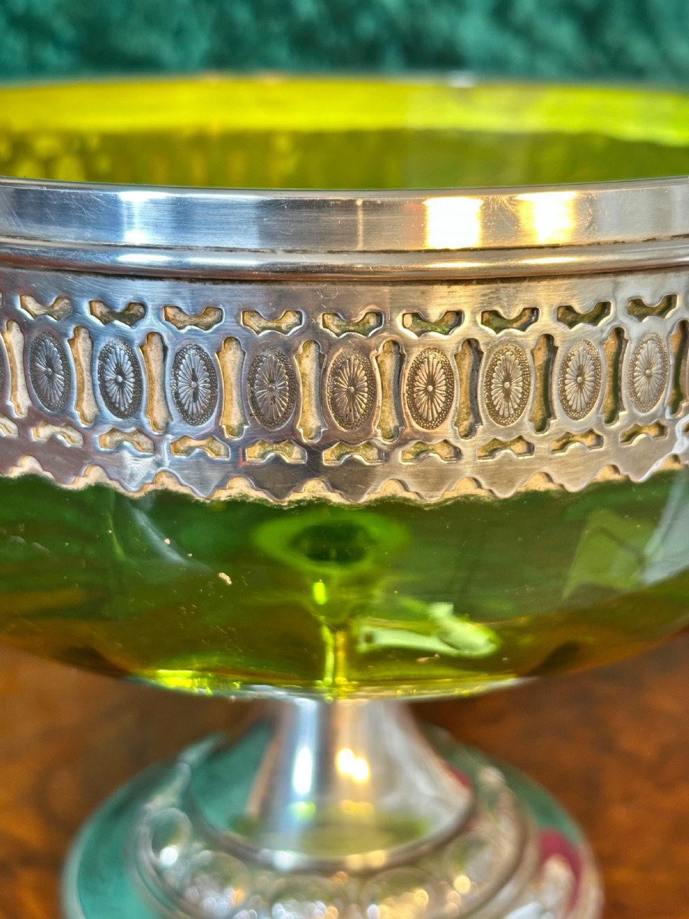 An Art Nouveau silver-plated pedestal basket featuring an ornate swing handle, pierced filigree decorative band, and a green glass liner. View VIII