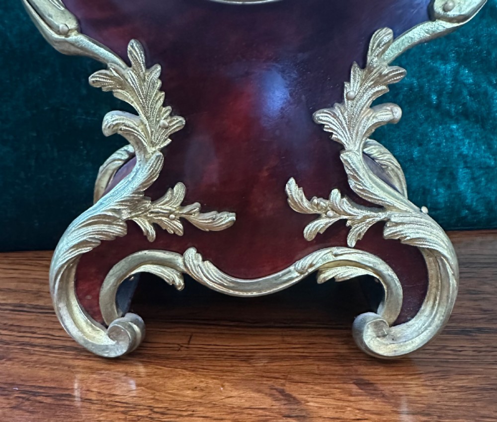 A 19th-century Victorian mantel clock in the Louis XV style featuring a dark veneered balloon case with gilded metal foliage mounts and a white enamel dial. View II