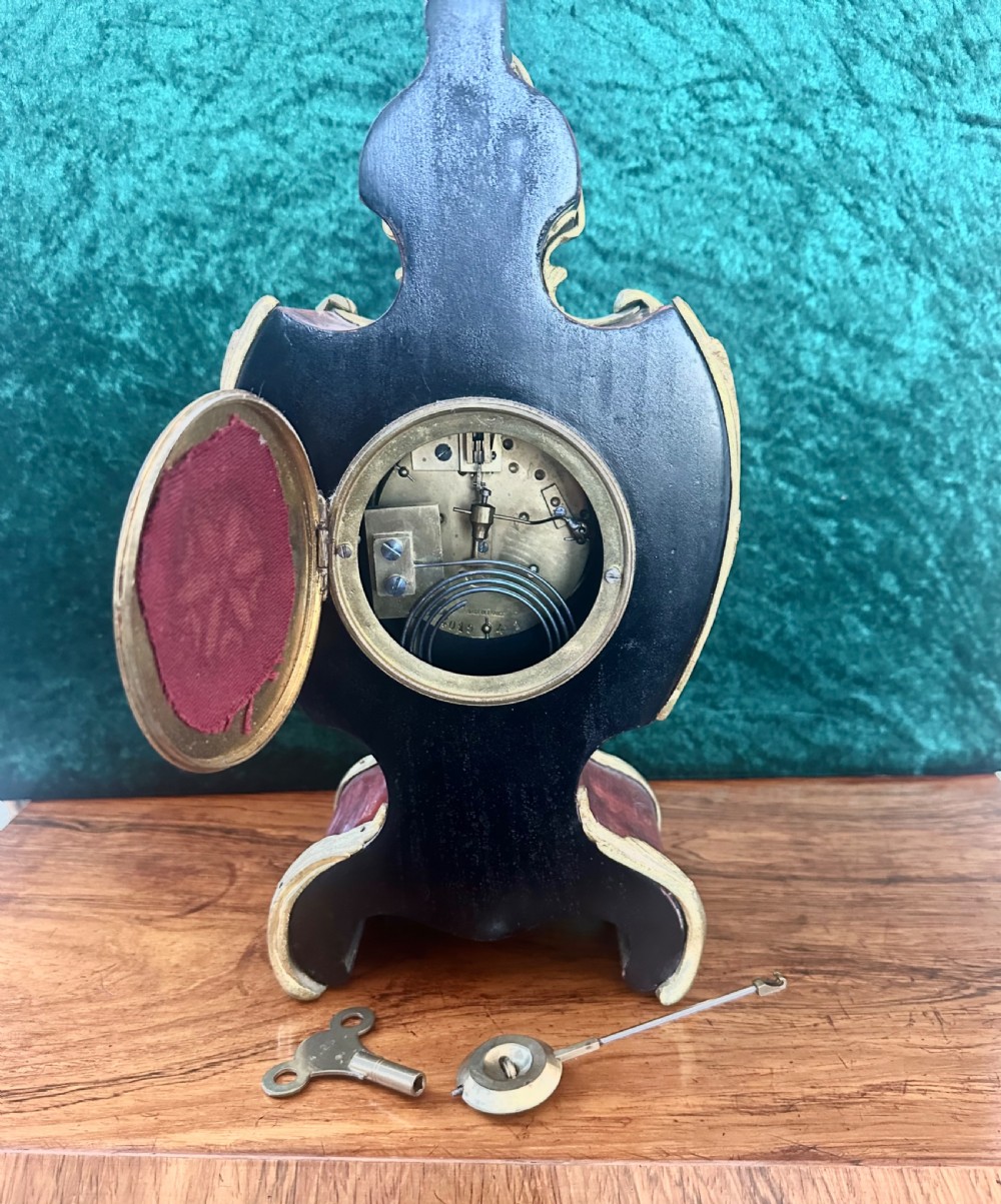 A 19th-century Victorian mantel clock in the Louis XV style featuring a dark veneered balloon case with gilded metal foliage mounts and a white enamel dial. View VII