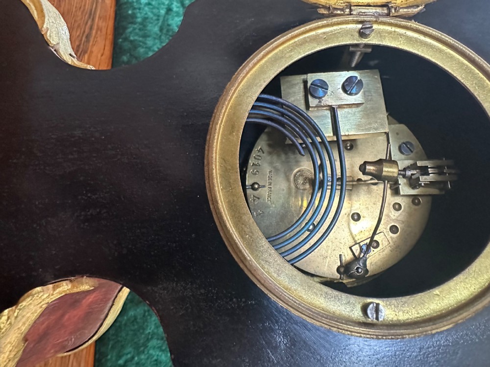 A 19th-century Victorian mantel clock in the Louis XV style featuring a dark veneered balloon case with gilded metal foliage mounts and a white enamel dial. View VIII