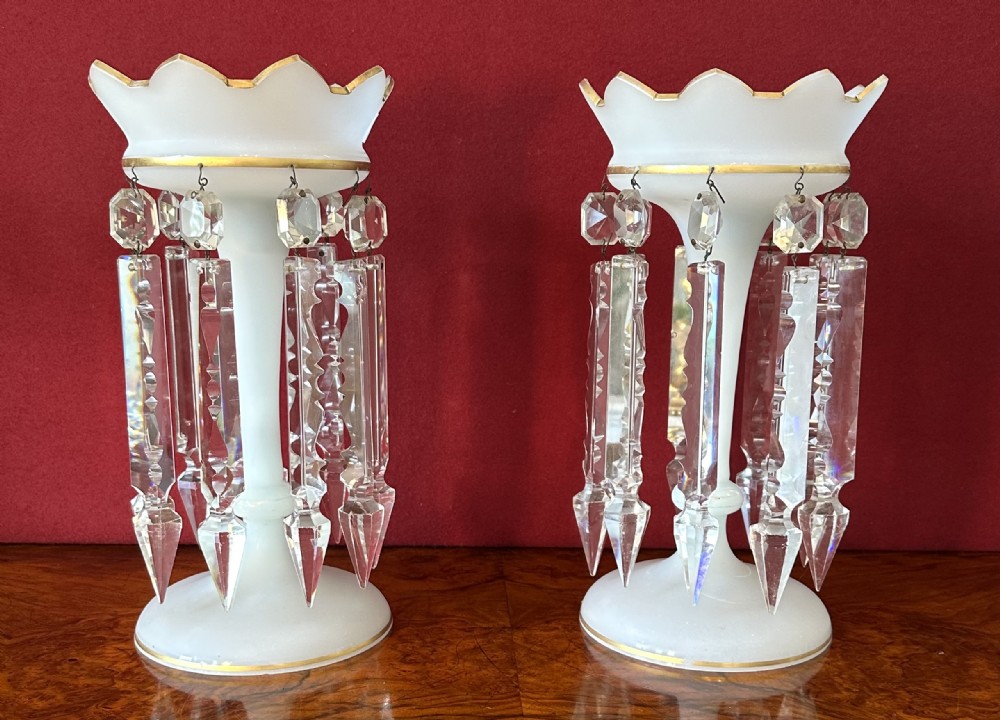 A pair of Victorian frosted white glass lustres featuring crenellated gilt-rimmed tops and suspended clear cut-crystal spearhead prisms.